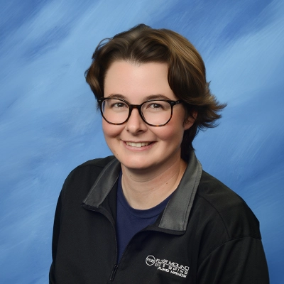 Office Manager Miranda Olson Smiling In Front Of Blue Background