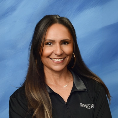 Receptionist Sara Hurst Smiling In Front Of Blue Background