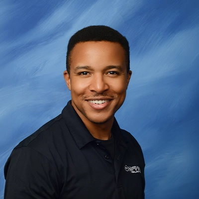 Rehab Specialist Wesley Smiling In Front Of Blue Background
