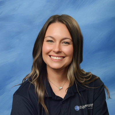 Chiropractor Brittany Pando Smiling In Front Of Blue Background